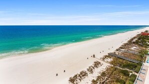 Une plage avec un ciel dégagé, un rivage sablonneux et quelques constructions le long de la côte.