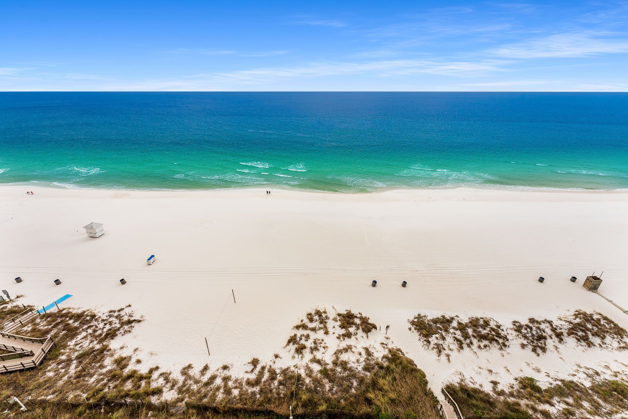 Una playa con cielo despejado, mar tranquilo y orilla arenosa.