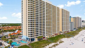 Un hôtel de grande hauteur doté de nombreux balcons, d’un espace piscine et situé en bord de mer.