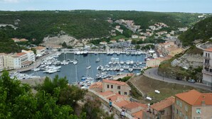 A coastal town with a marina filled with boats, surrounded by terraced houses and greenery. - CORSICA: LOUNICELI Villa with air conditioning, a pool, beaches, shops, and mountains (Zonza)