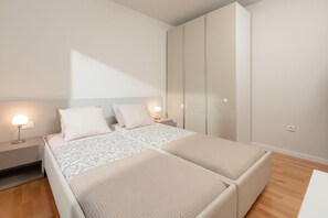 A bedroom with two beds, nightstands with lamps, a wardrobe, and a wooden floor. - A private oasis just 5 minutes from Diocletian's Palace (Split)