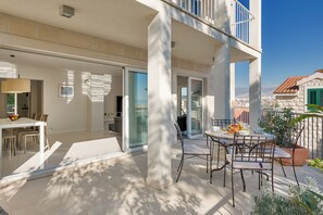 A modern outdoor patio with a dining table and chairs, a large pillar, and a view of the cityscape. - A private oasis just 5 minutes from Diocletian's Palace (Split)