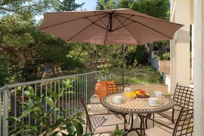 An outdoor patio with a round table, chairs, and a large umbrella. - A private oasis just 5 minutes from Diocletian's Palace (Split)