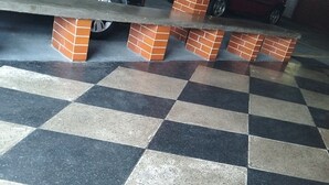 Un parking dont le sol est recouvert d’un motif à carreaux et qui est soutenu par des piliers en briques.