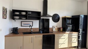 Eine moderne Küche mit Geschirrspüler, Kaffeemaschine, Mikrowelle und einem schwarzen Backofen.