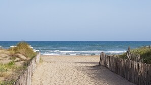 A sandy beach path leading to the ocean with a wooden fence on one side. - Marseillan Plage: Fleur des Dunes Vacation Home—3 Bedrooms, Sleeps 6 (Marseillan)