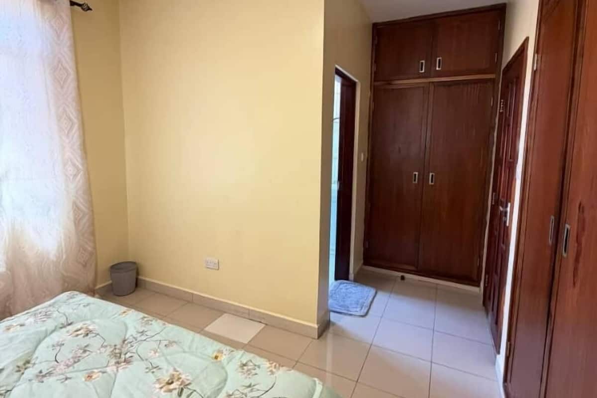 Une chambre à coucher comprenant un lit, une armoire et une porte donnant sur une autre pièce.