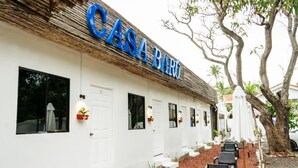 A building with a sign reading "CASA BAR" and a row of outdoor seating with chairs and tables.