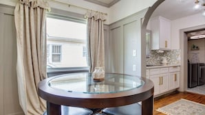 Een moderne keuken met witte kasten, een glazen tafel en uitzicht op buiten.