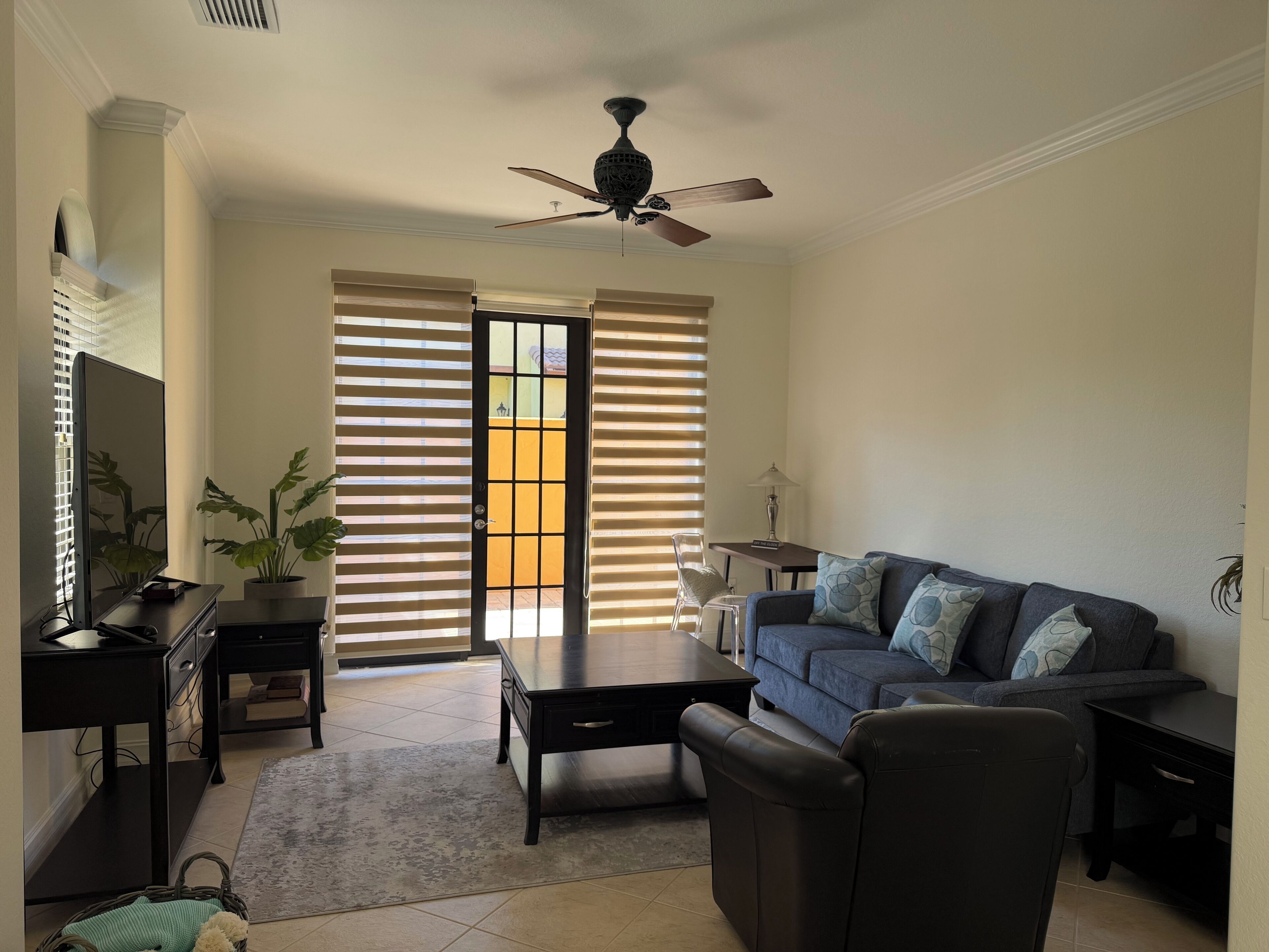 A living room with a sofa, coffee table, TV, and a ceiling fan.