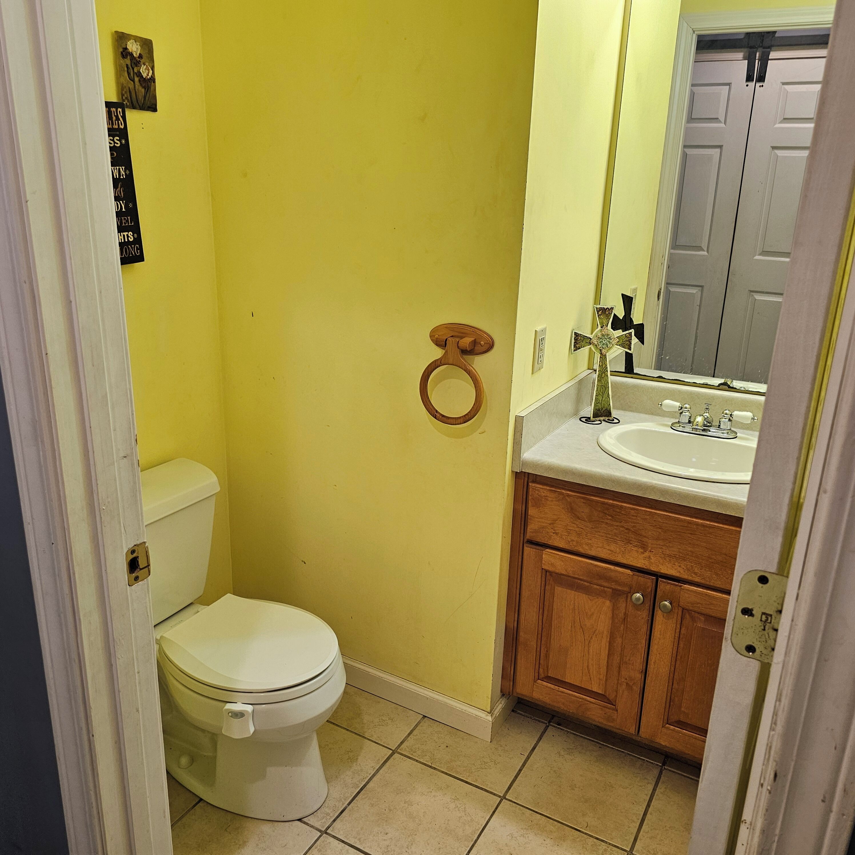 Een kleine badkamer met toilet, wastafel en spiegel.