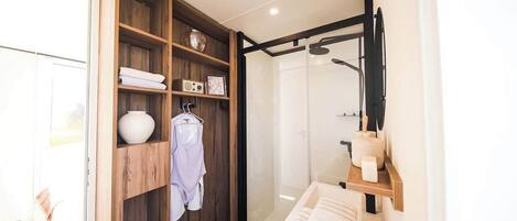 A modern bathroom with a glass shower enclosure, a wooden vanity with a sink, and a towel rack.