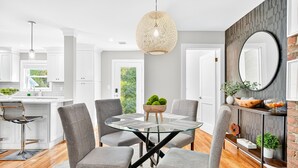 A modern kitchen with white cabinets, a round glass table, and grey chairs. - Charming Renovated Home, Cozy for All! Pet friendly! (New Windsor)