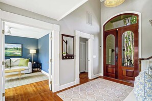 A hallway with a wooden floor, a white door, and a blue wall with a painting. - Harbour Town retreat w/ pool & BBQ grill (Hilton Head Island)