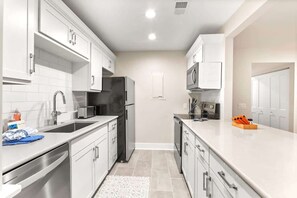 A modern kitchen with white cabinets, stainless steel appliances, and a white countertop. - Coastal Retreat with Private Balcony & Pool Access (Hilton Head Island)