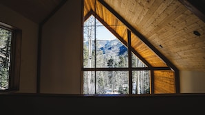 A room with a large window and a sloped wooden ceiling.