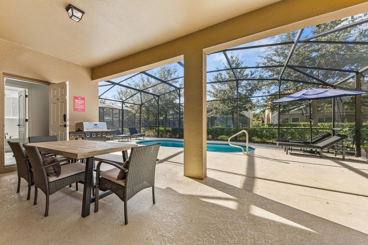 Une terrasse extérieure avec une piscine, des chaises longues et un espace barbecue.