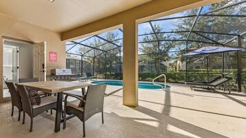 Une terrasse extérieure avec une piscine, des chaises longues et un espace barbecue.