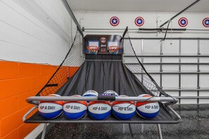 Ein Basketball-Zielspiel mit fünf Basketballsäulen mit der Aufschrift 'POP-A-SHOT' und einem gesicherten Wurfbereich.