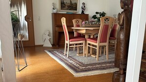 Et spiseområde med et træbord, røde polstrede stole og et tæppe med et mønster.