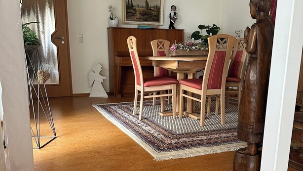 A dining area with a wooden table, red upholstered chairs, and a patterned rug. - Vacation apartment RIVA (Kronau)