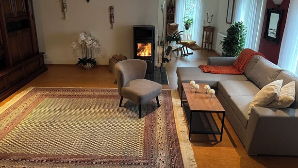 En stue med pejs, sofa, lænestol og et mønstret tæppe.