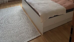 Et soveværelse med seng, et vindue med gardiner, en radiator og en væg med pynt.