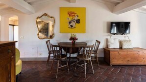 A dining area with a round table, wooden chairs, a mirror, a television, and a poster on the wall. - Pitti Art by MMega Homes and Villas (Florence)