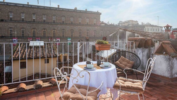 A rooftop terrace with a round table, white metal chairs, and a view of a historic building. - Pitti Art by MMega Homes and Villas (Florence)