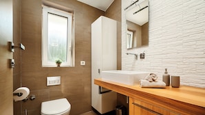 Ein modernes Badezimmer mit Toilette, Waschbecken und Spiegel.