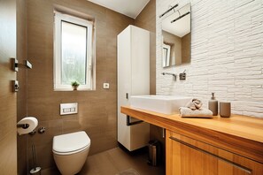 Ein modernes Badezimmer mit Toilette, Waschbecken und Spiegel.