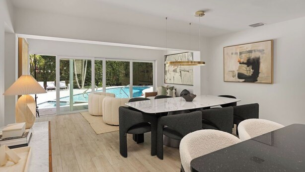 Un espace repas moderne avec vue sur la piscine, une grande table et des sièges confortables.