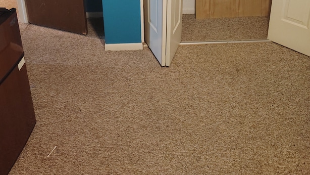 Ein Zimmer mit einer braunen Tür, einer blauen Wand und einer weißen Tür mit Lamellen.