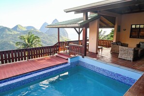 Une piscine avec une terrasse en bois et une vue sur les montagnes.
