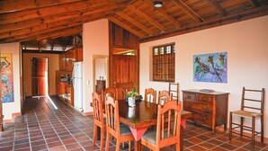 Un comedor con una mesa y sillas de madera, un refrigerador y un cuadro en la pared.