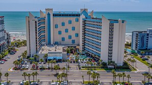 A large hotel with multiple floors, a central courtyard, and a view of the ocean. - 💎Oceanfront | Amazing Views | Relax in Luxury | Ocean Reef Resort 818💎 (Myrtle Beach)