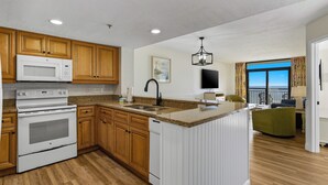 A modern kitchen with wooden cabinets, a white stove, and a large island. - 💎Oceanfront | Amazing Views | Relax in Luxury | Ocean Reef Resort 818💎 (Myrtle Beach)