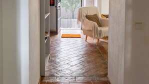 A hallway with a tiled floor, an archway, a chair, and a door leading to a room with a window. - Cottage in the Guadiana valley, near Mértola (Portugal) (Mértola)