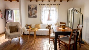 Ein gemütliches Zimmer mit Holzboden, einem Esstisch mit Stühlen, einer Couch, einem kleinen runden Tisch und einem Schrank.