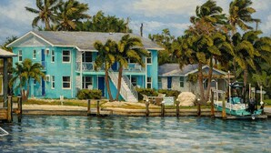 Un bâtiment à deux étages, à la façade bleue, avec un quai et un bateau.