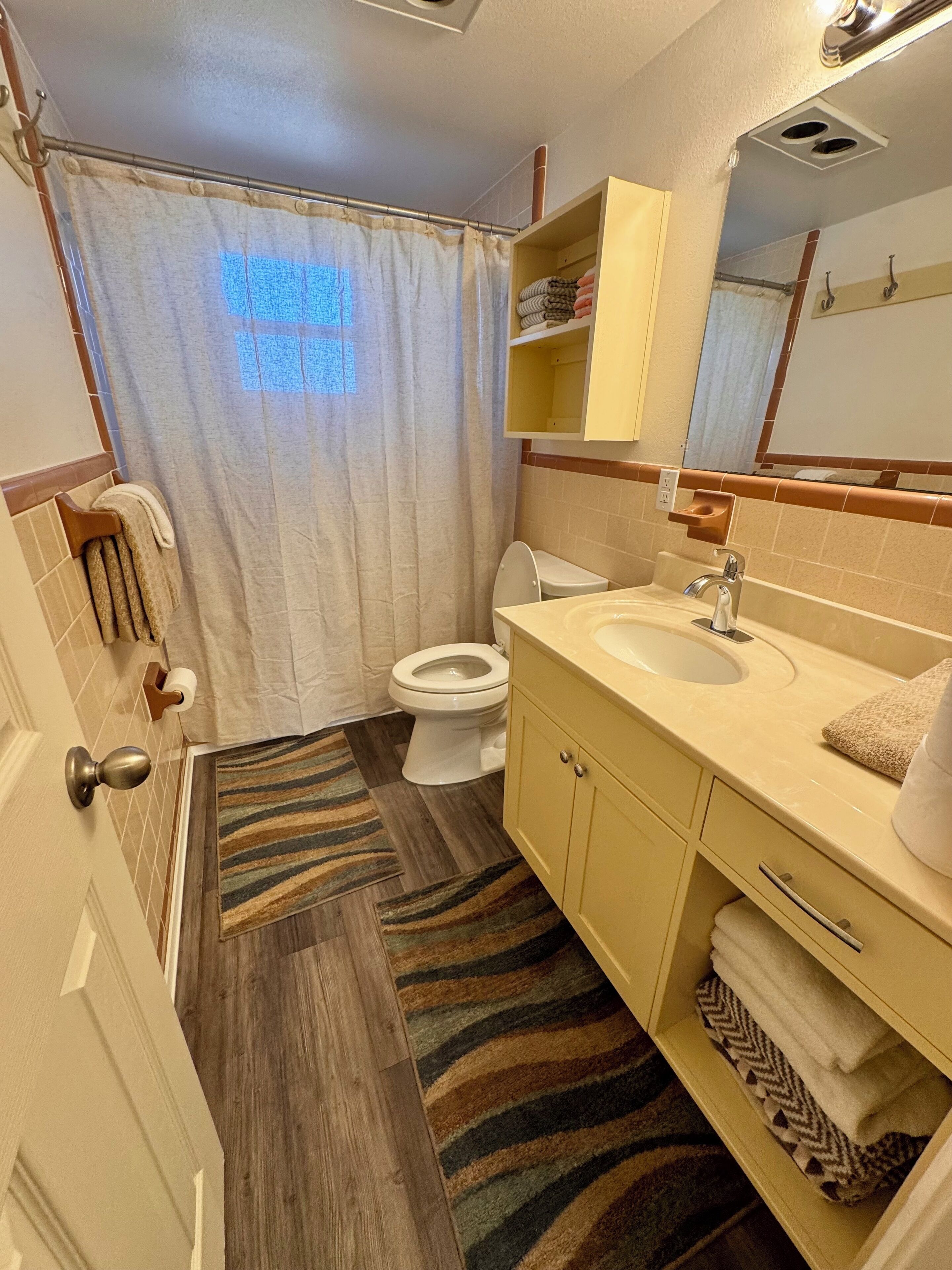 A bathroom with a toilet, sink, mirror, towel rack, and a shower curtain.