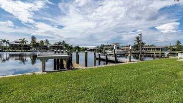 A marina with boats docked, a grassy area in the foreground, and buildings in the background.