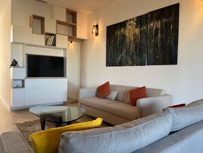 Un salon moderne avec un canapé, une table basse en verre et un téléviseur à écran plat.