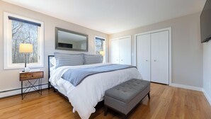 A bedroom with a bed, a nightstand, a bench, a dresser, and a mirror. - Charming 3-bedroom house with AC in peaceful Tiverton (Tiverton)