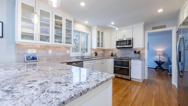 A modern kitchen with white cabinetry, granite countertops, stainless steel appliances, and a built-in microwave. - Charming 3-bedroom house with AC in peaceful Tiverton (Tiverton)