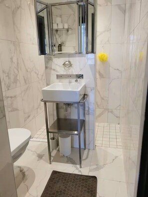 A bathroom with a white sink, a mirror, and a shower enclosure. - Charming Bordeaux Apartment: 2 Bedrooms, Free Park (Bordeaux)