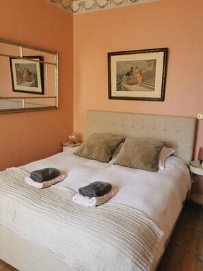 A bedroom with a bed, two pillows, a nightstand, a lamp, and two framed pictures on the wall. - Charming Bordeaux Apartment: 2 Bedrooms, Free Park (Bordeaux)