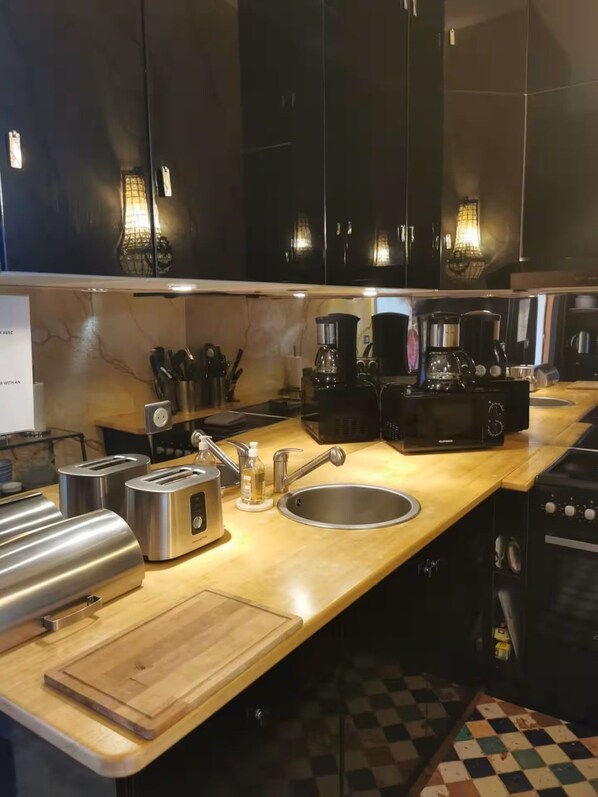 Una cucina con pensili neri, elettrodomestici in acciaio inossidabile e pavimento a scacchi.