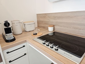 Eine moderne Küche mit integriertem Induktionskochfeld, einer Kaffeemaschine, einem Wasserkocher und einem Toaster.