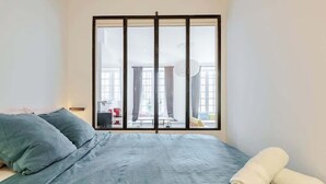 Ein Schlafzimmer mit großem Fenster, einem Bett mit grüner Bettwäsche und zwei Handtüchern.